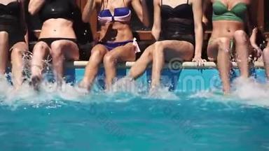在一个夏日聚会上，<strong>女孩</strong>们<strong>喝</strong>着五颜六色的饮料，坐在<strong>游泳</strong>池里，双腿在水中飞溅。 慢速运动